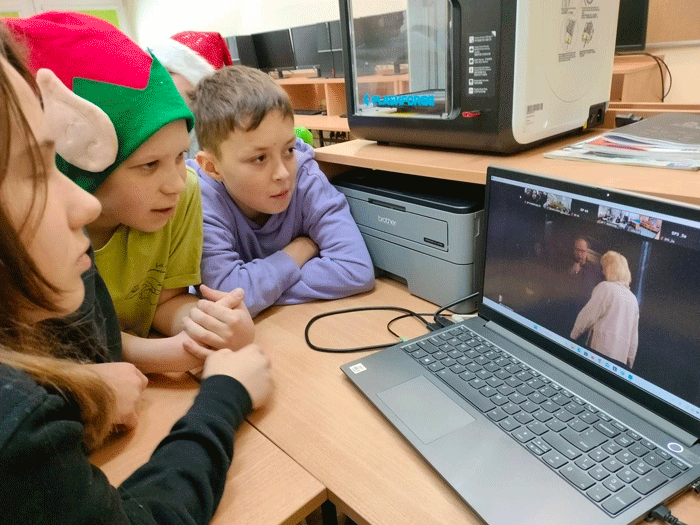 Grafika przedstawia trzech uczniów z klasy 5a oglądających konferencje Fair Friends na laptopie