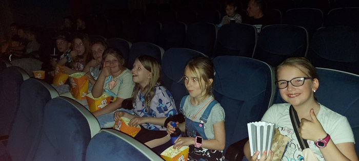 Grafika przedstawia uczniów z klasy 3c w sali kinowej